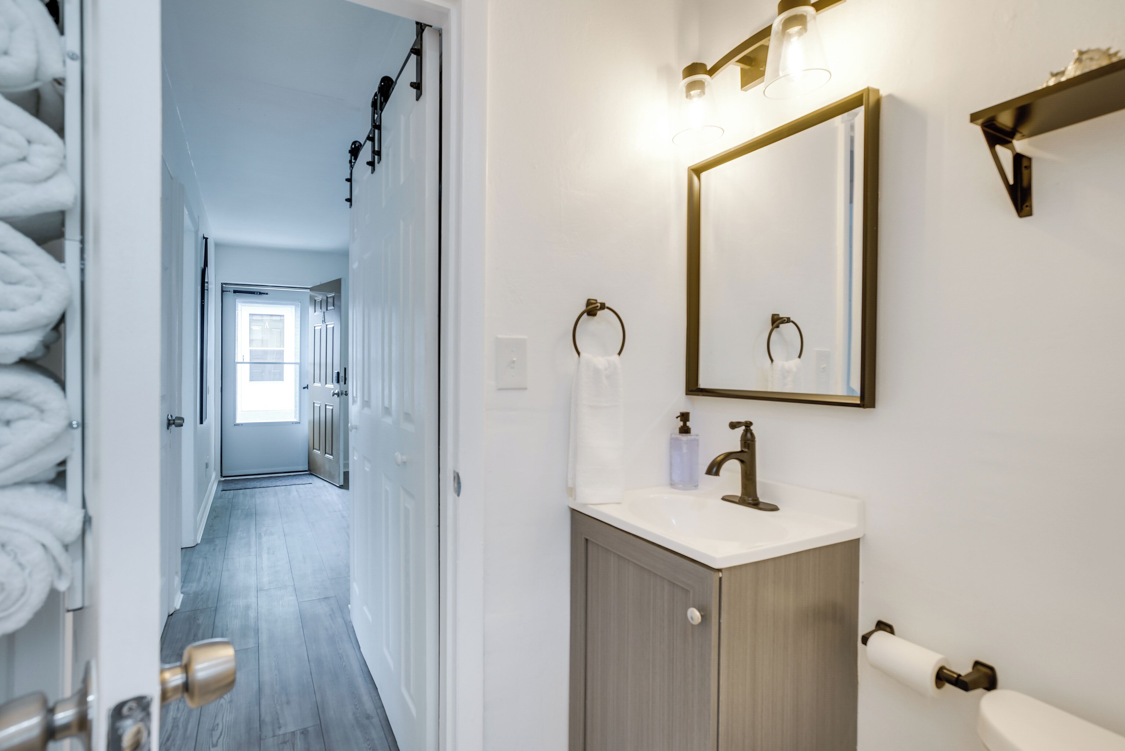 Un baño con lavamanos, espejo, toallero y retrete.