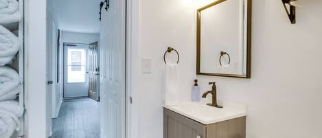 Un baño con lavamanos, espejo, toallero y retrete.