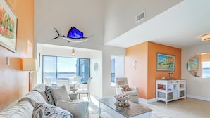A spacious living area with a sofa, coffee table, and a view of the ocean through large windows. - Key Retreat: Bay Views & Private Beach Access (Englewood)