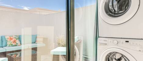 A laundry area with stacked washing machines and a glass partition.