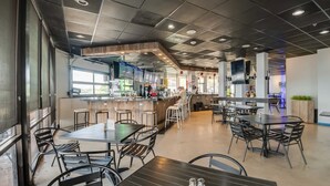 A modern restaurant with a bar area, multiple seating options, and a visible kitchen. - Lake Conroe Condo: Balcony, Views & Pool Access! (Willis)
