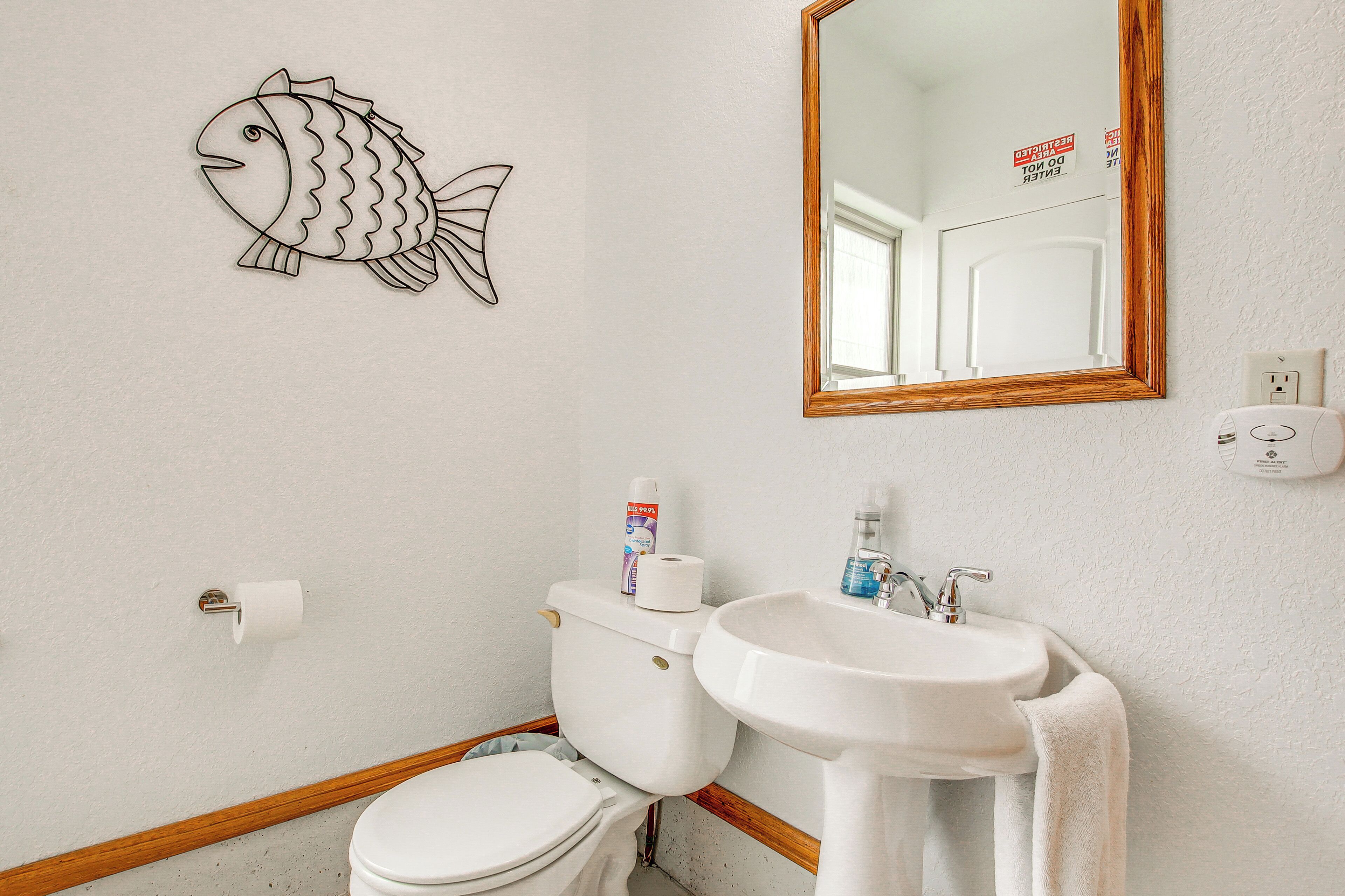 A bathroom with a toilet, sink, and mirror.