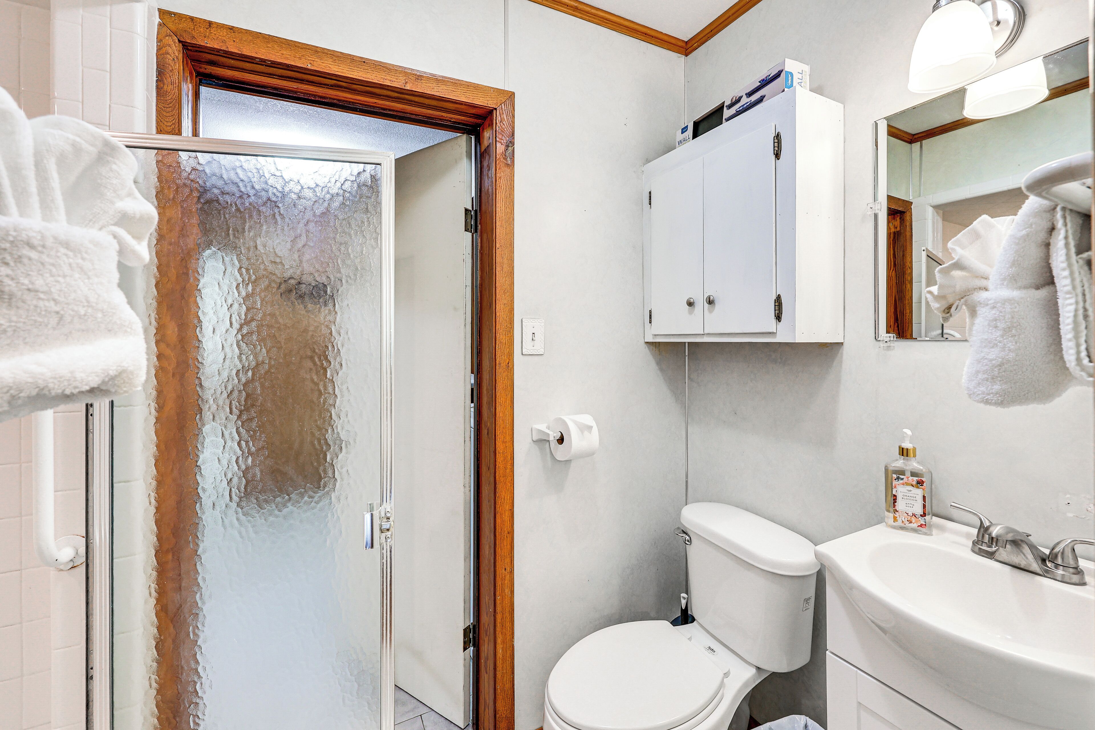 A bathroom with a white toilet, a sink with a soap dispenser, and a towel rack.