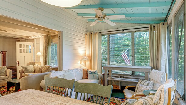 A cozy room with a dining table, two chairs, a sofa, and a window with curtains. - ~ 1 Mi to Dtwn Grand Haven: Lake Michigan Cabin (Grand Haven)