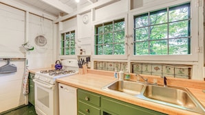 A kitchen with a stove, oven, and sink, wooden cabinets, and a window with a view of trees. - ~ 1 Mi to Dtwn Grand Haven: Lake Michigan Cabin (Grand Haven)