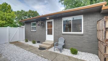 A modern house with a gray brick exterior, a white door, and a gray chair outside.
