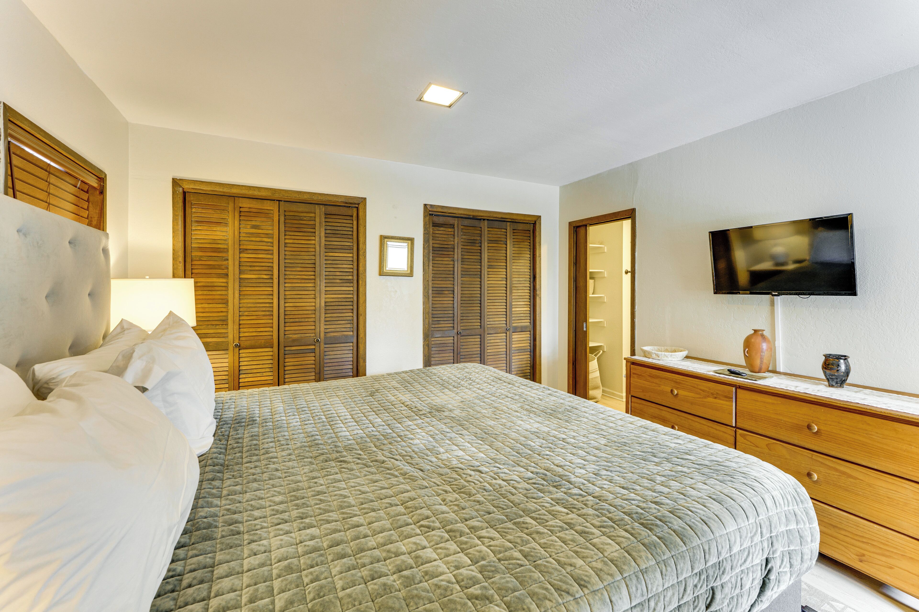 A bedroom with a bed, wooden wardrobe, a television, and a dresser.