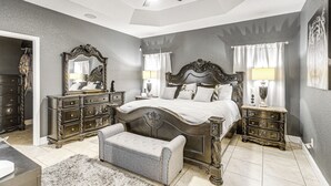 Una camera da letto con un letto grande, due comodini, una panca, una cassettiera e un ventilatore a soffitto.