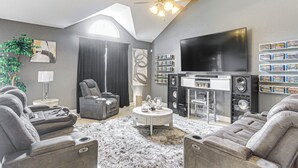 Un soggiorno moderno con una TV a schermo piatto, un ventilatore a soffitto e un camino.
