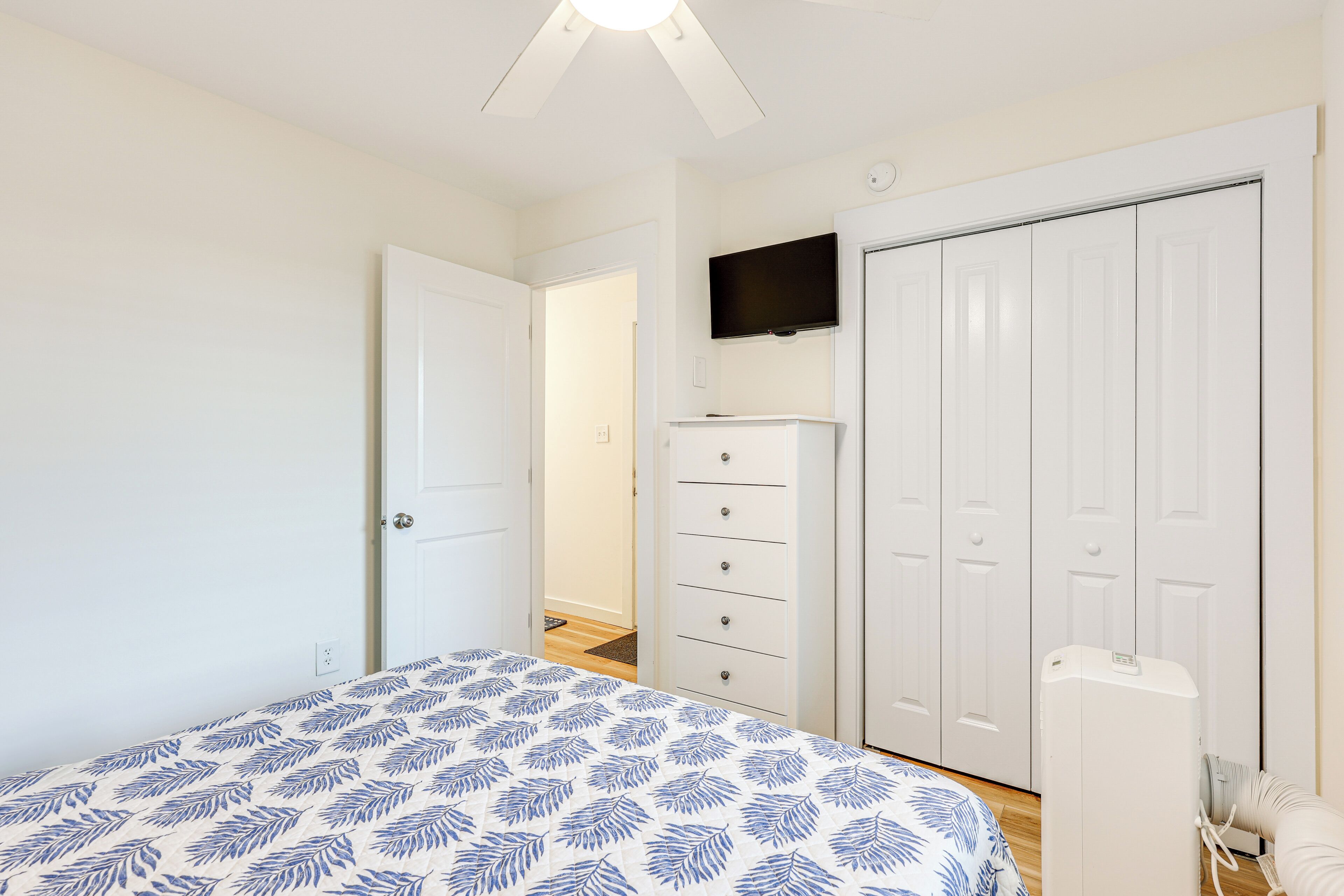 Ein Schlafzimmer mit Bett, Kleiderschrank, Fernseher und Heizung.
