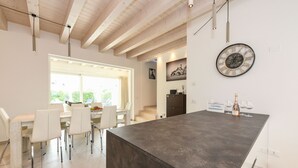 Une cuisine moderne dotée d’un grand îlot central, de chaises blanches et d’une table à manger.