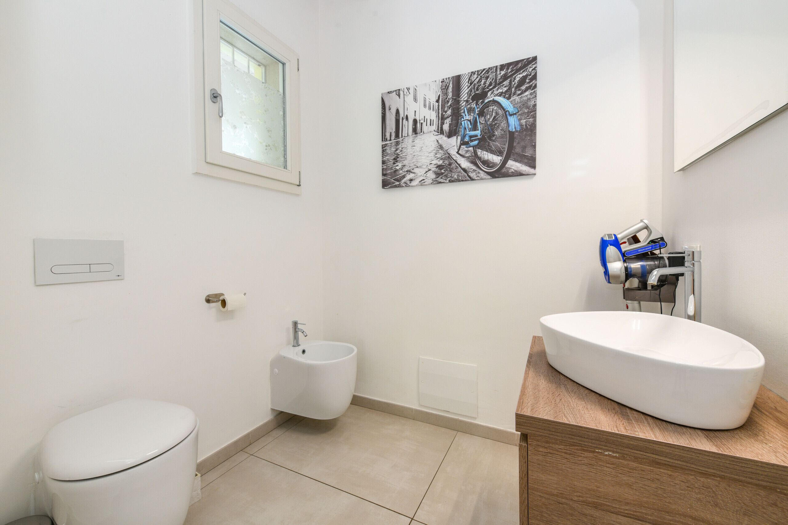 A modern bathroom with a toilet, bidet, and a large oval sink.
