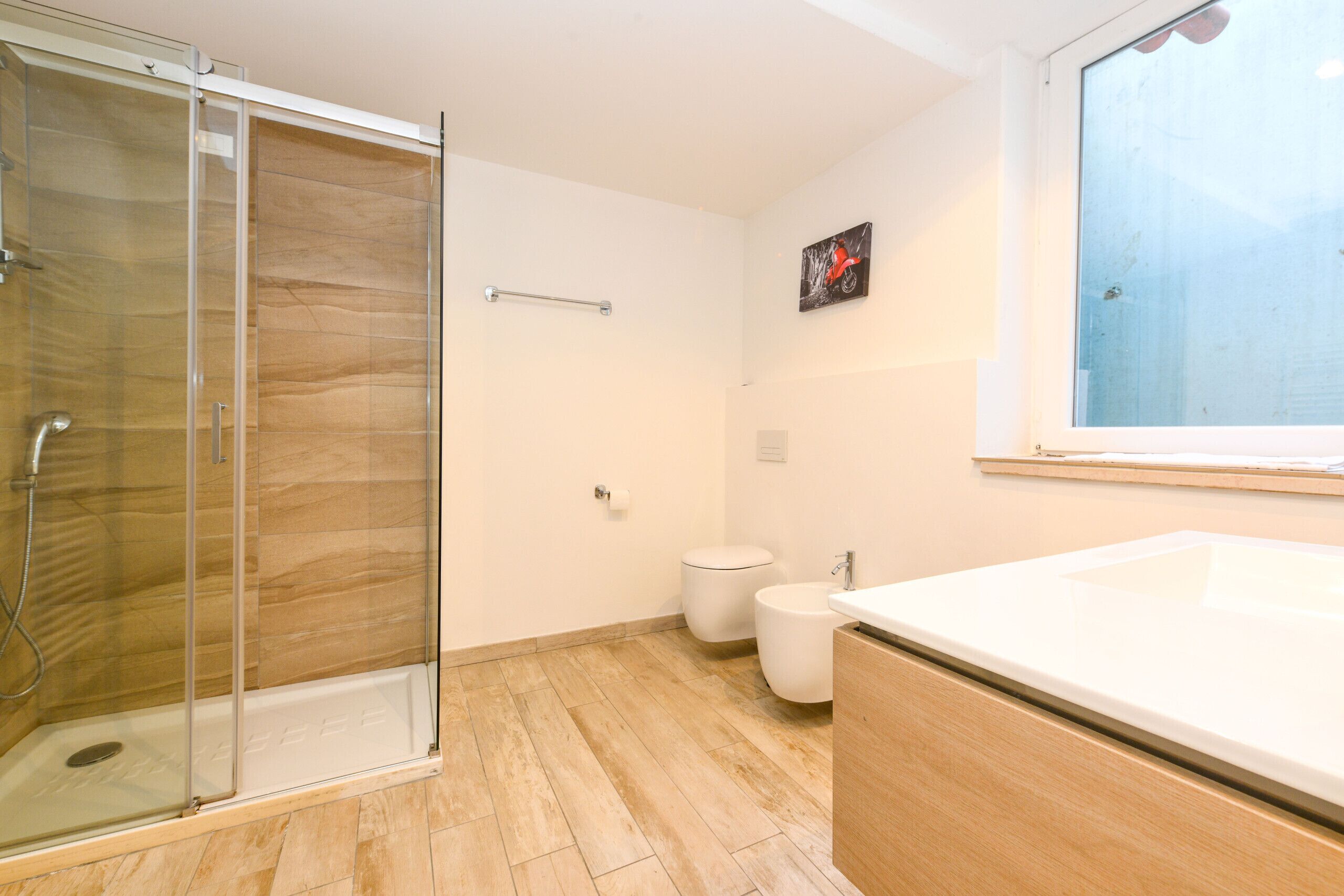 Une salle de bain moderne avec une douche à parois de verre, des toilettes blanches et un grand lavabo.