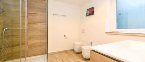 Une salle de bain moderne avec une douche à parois de verre, des toilettes blanches et un grand lavabo.