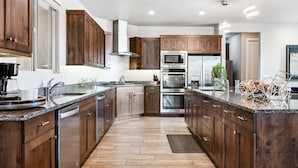 A modern kitchen with wooden cabinets, stainless steel appliances, and a granite countertop.