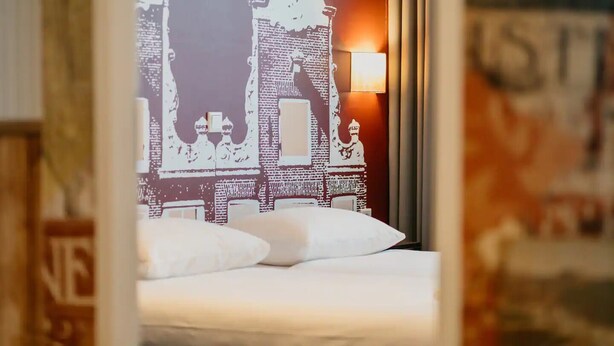 A bed with white linens in a room with a mural of a building on the wall. - The Perfect Amsterdam Apartment accommadtes 6!! (Amsterdam)