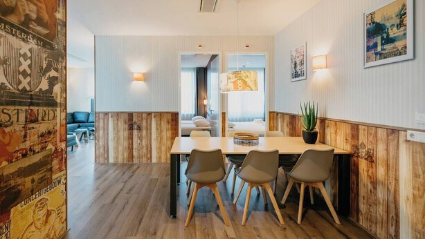 A modern dining area with a wooden accent wall, a central table with chairs, and a potted plant.
