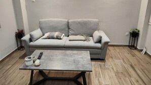 A modern living room with a grey sofa, two wall-mounted lights, a coffee table, and a potted plant.