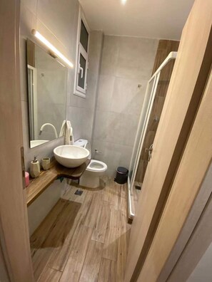 A modern bathroom with a large sink, toilet, and shower area.