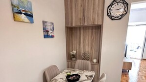 A dining area with a marble table, four chairs, and a wooden cabinet. - Nature House - At093 (Athens)
