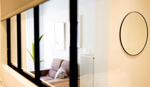A room with a sofa, a radiator, and a wall-mounted mirror. - Happy Place -- At042 (Athens)