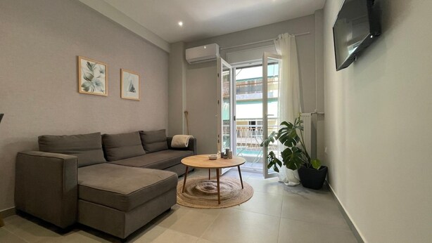 A modern living room with a sofa, a small round table, and a potted plant. - Eunoia Apartment - At062 (Athens)