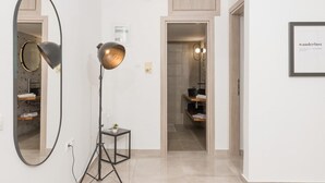 Un pasillo con un espejo grande, una lámpara de pie y un cartel enmarcado en la pared.