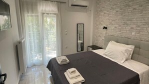 Un dormitorio moderno con una cama grande, una pared de ladrillo decorativa y un ventanal corredero que da a un balcón.