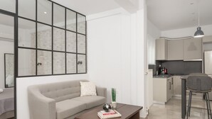 Una sala de estar moderna con un sofá, una mesita de centro y una cocina al fondo.