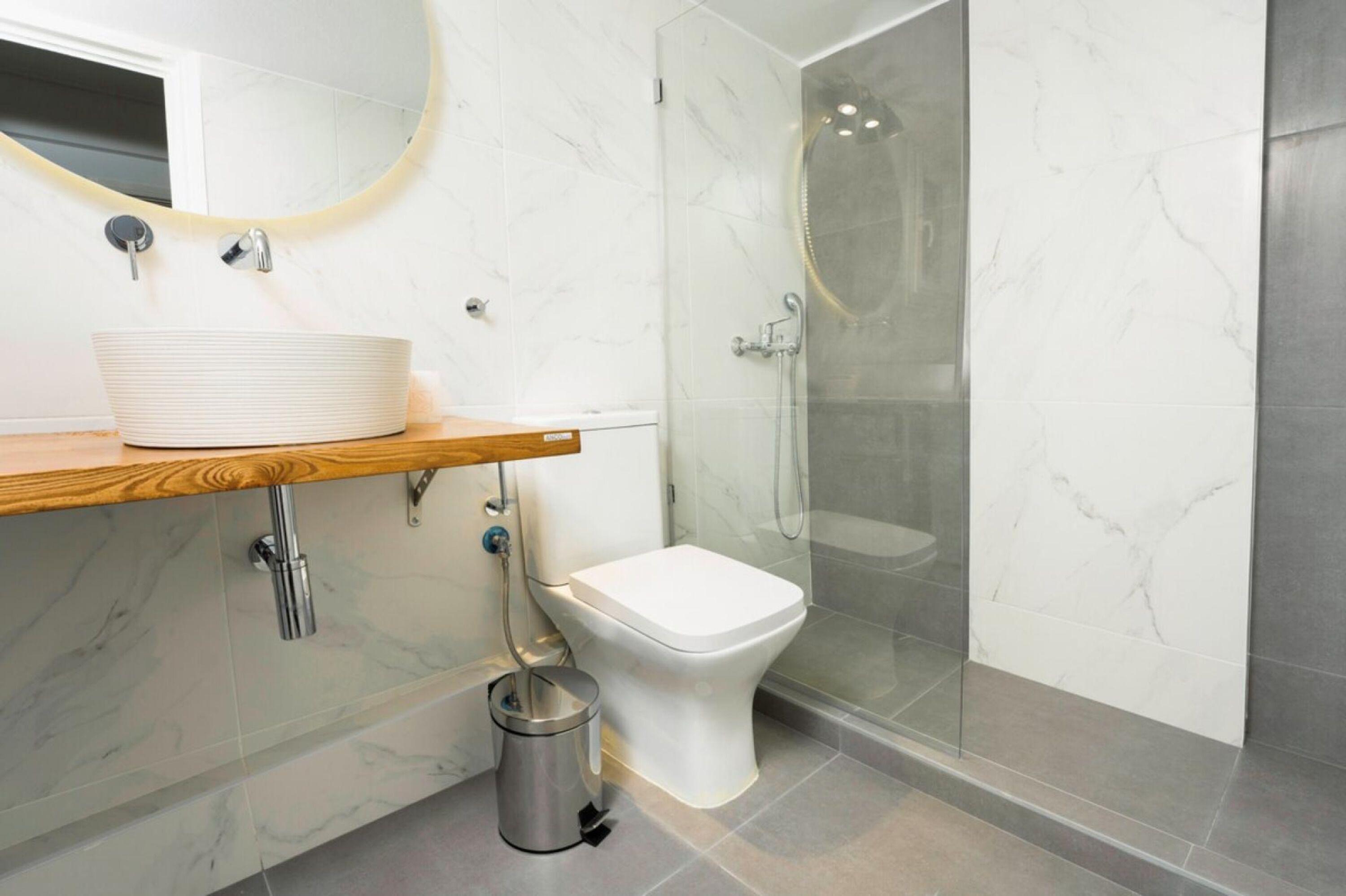 Ein modernes Badezimmer mit Marmorwaschbecken, Toilette und einer Duschkabine.