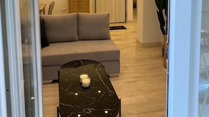 Ett modernt vardagsrum med en soffa, en glasdörr och ett litet bord med ljus.