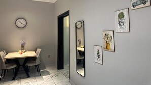 Un comedor con una mesa de madera, cuatro sillas, un reloj de pared y varias fotos enmarcadas.