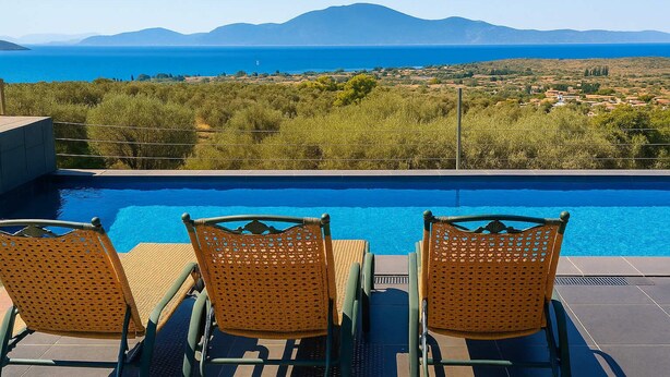 Un espace aménagé au bord de la piscine, avec des fauteuils en osier et une vue sur la mer et les montagnes.