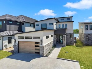 A modern two-story house with a garage, stone accents, and a well-maintained lawn.