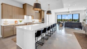 A modern kitchen with a large island, wooden cabinets, and pendant lighting. - Lone Star Landing II | Concierge Services (Kingsland)
