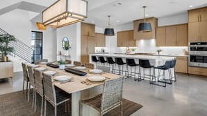 A modern kitchen with a central island, wooden cabinets, and black bar stools. - Lone Star Landing II | Concierge Services (Kingsland)