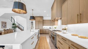 A modern kitchen with white countertops, wooden cabinets, and stainless steel appliances. - Lone Star Landing II | Concierge Services (Kingsland)