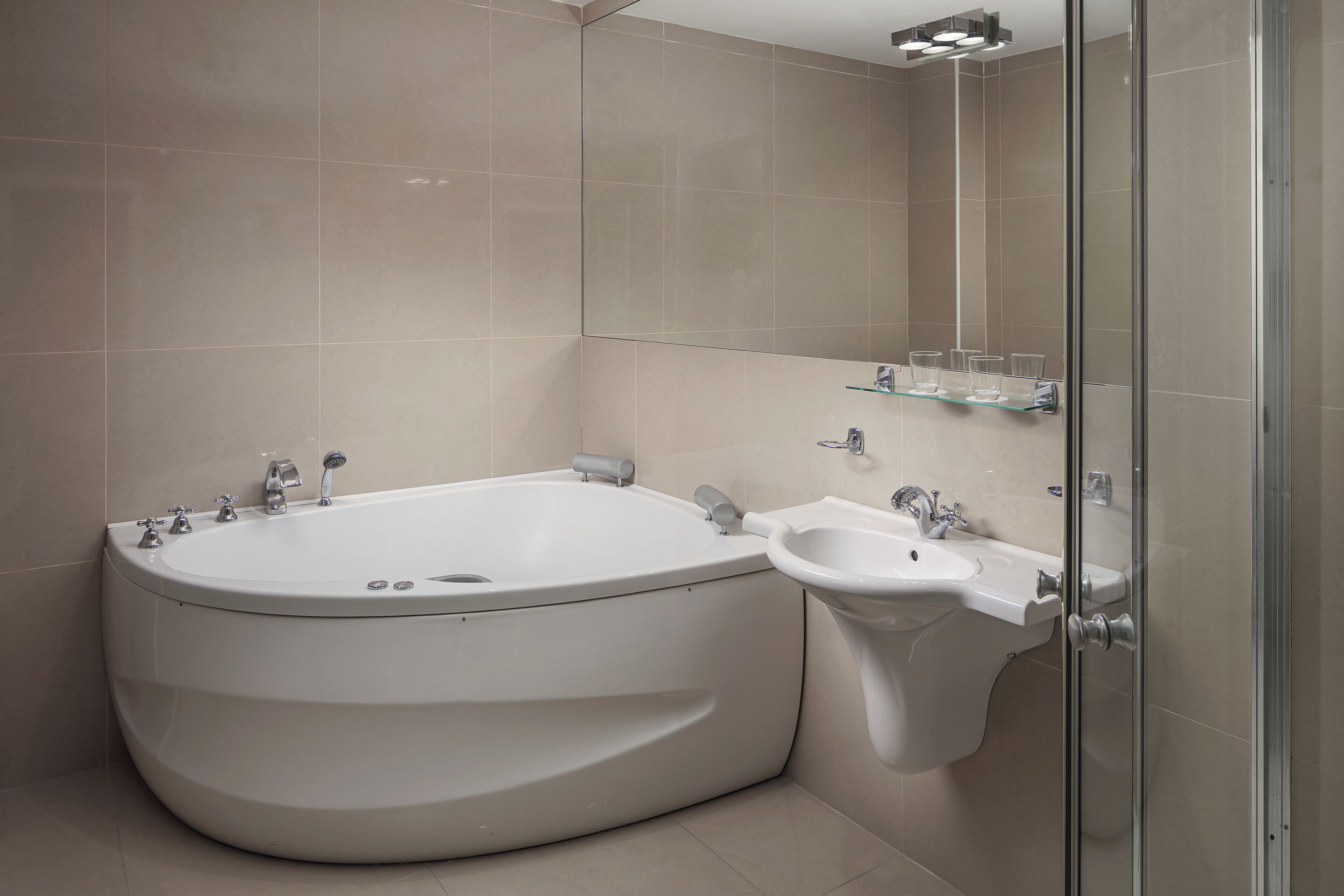 A modern bathroom with a freestanding bathtub, a pedestal sink, and a glass shower enclosure.