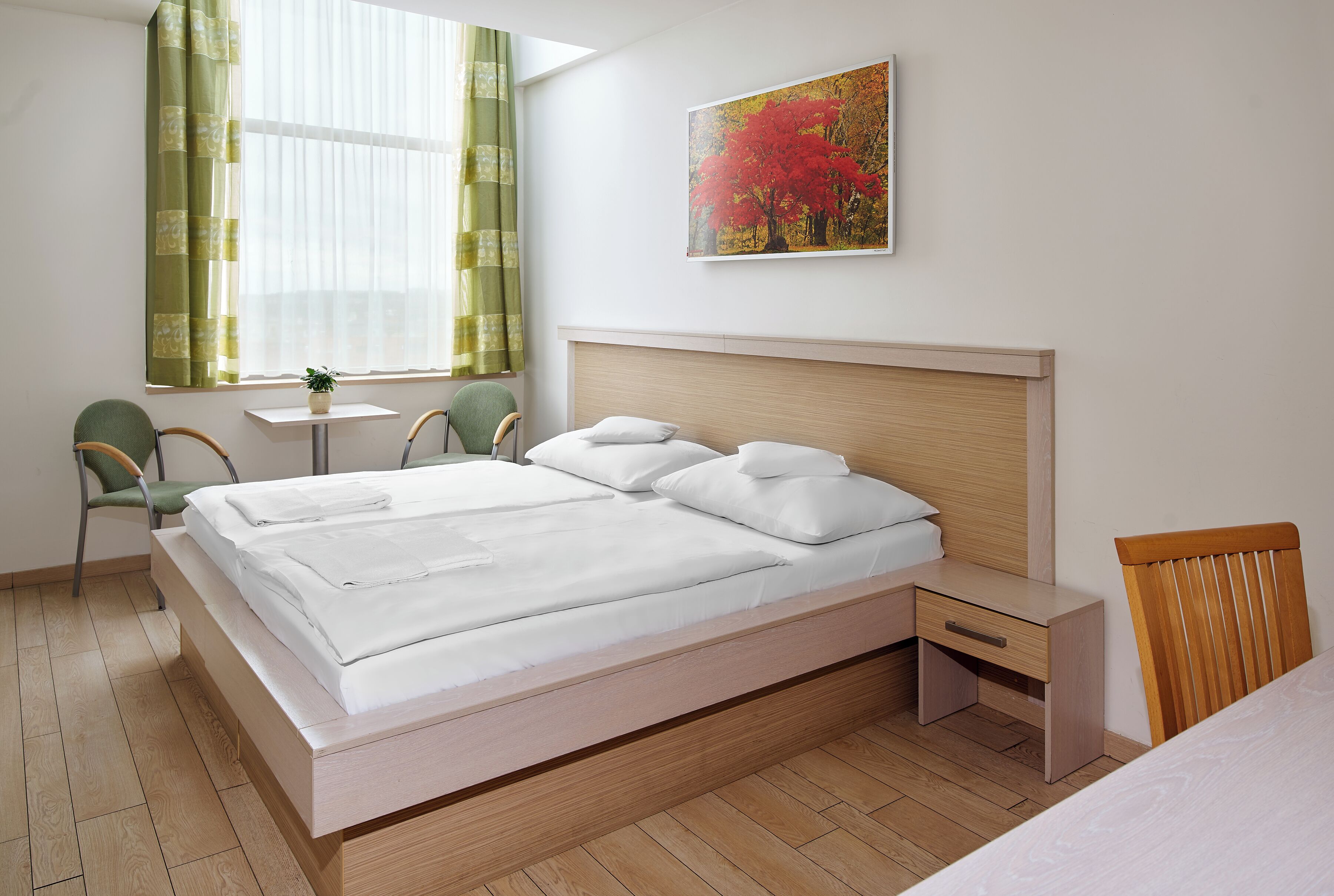 A modern bedroom with a large bed, bedside tables, a desk, and a chair.
