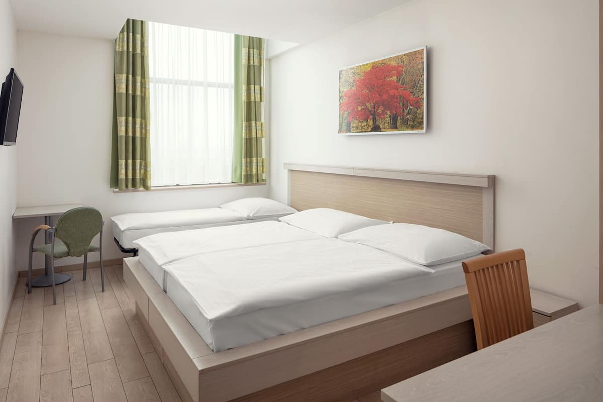 A modern bedroom with a large bed, a desk, and a chair.