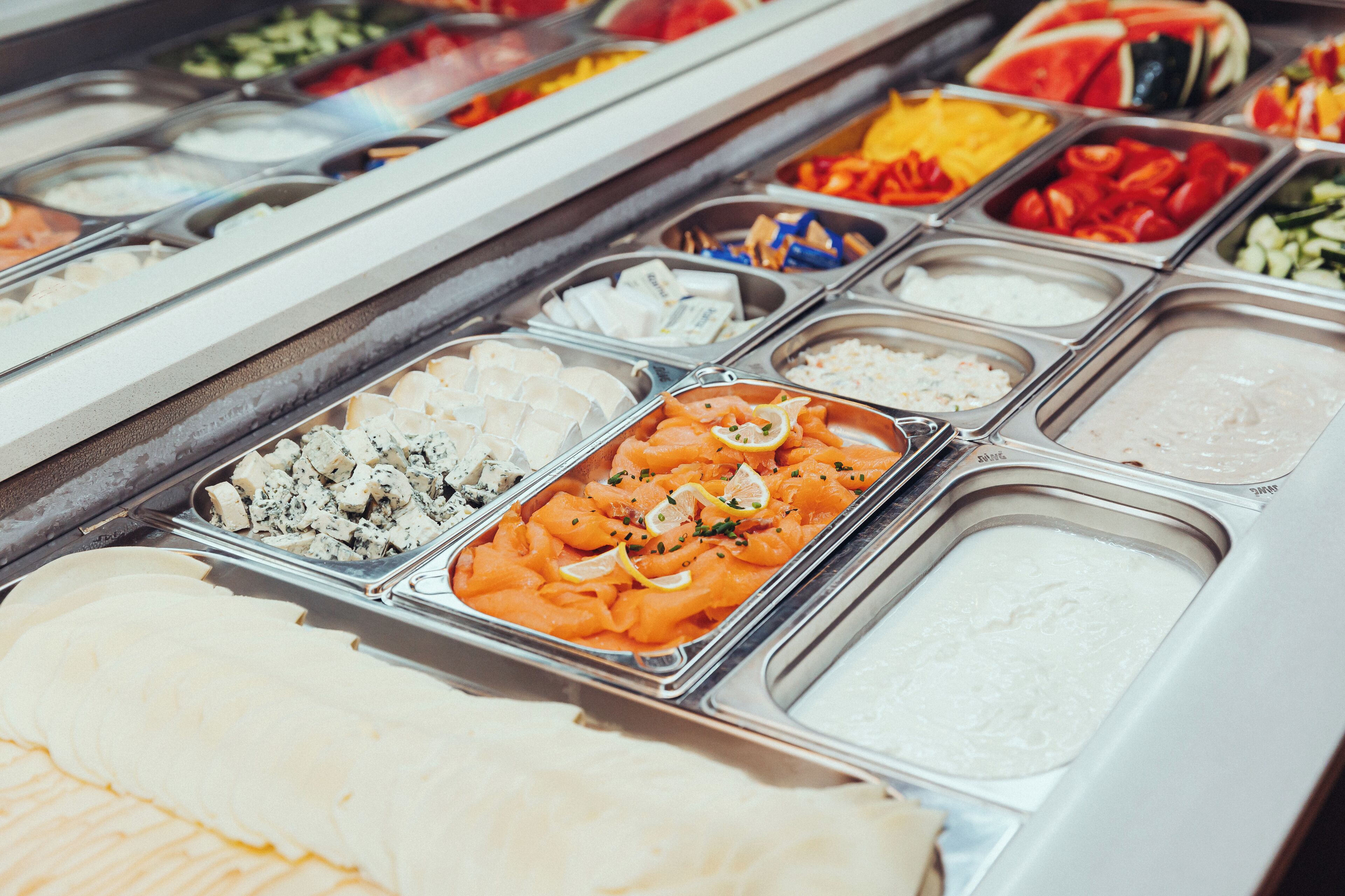 Un bufé con diversas opciones de comida, incluyendo carnes, quesos y ensaladas.