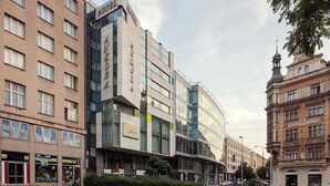 A modern hotel with a glass facade, multiple floors, and a classic building adjacent to it. - Ankora Hotel Prague (Prague)