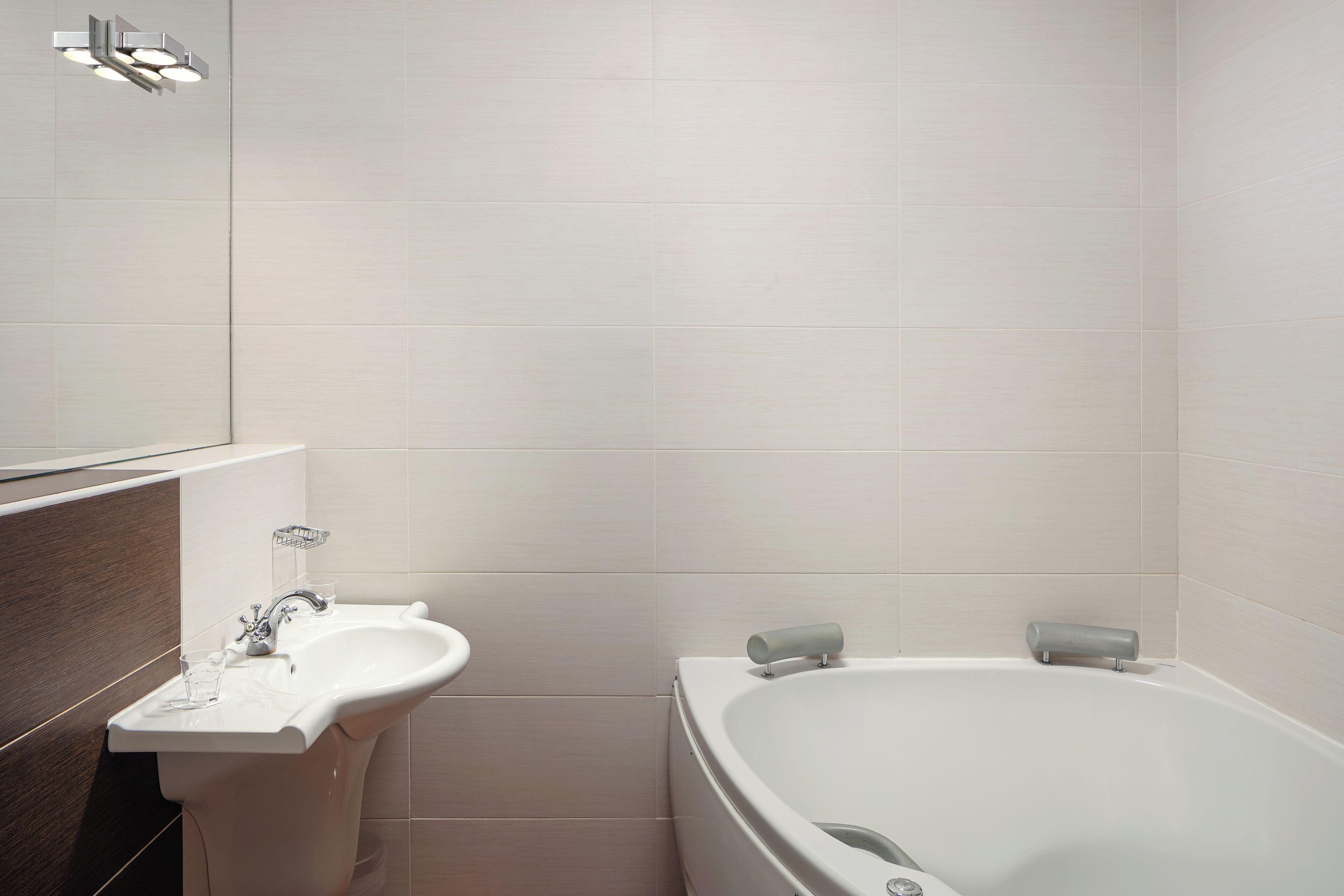 Une salle de bain moderne avec un lavabo blanc, un miroir et une baignoire.