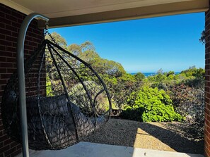 A hanging chair in a covered outdoor area with a view of the ocean and greenery. - Bunga Lodge @ Lakes Entrance 10 min walk to the beach and lake! (Lake Bunga)