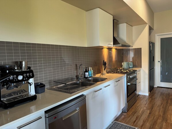 A modern kitchen with a built-in dishwasher, stove, and sink. - Bunga Lodge @ Lakes Entrance 10 min walk to the beach and lake! (Lake Bunga)