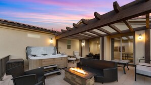 Une terrasse extérieure agrémentée d’un foyer en pierre, de meubles en osier et d’un espace salon abrité.