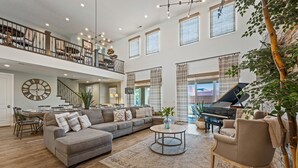 Un salon spacieux avec un canapé d’angle, une table basse ronde et un piano.