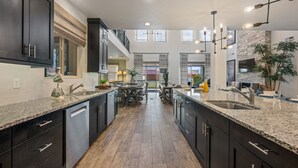 Une cuisine moderne avec des meubles de couleur sombre, des plans de travail en granit et un îlot central.