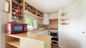 Une cuisine de taille réduite, équipée d’un four à micro-ondes, de meubles en bois et d’un évier.