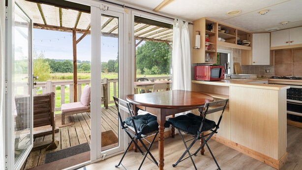 Une cuisine avec un coin repas, des portes-fenêtres coulissantes donnant sur une terrasse et une vue sur la verdure.